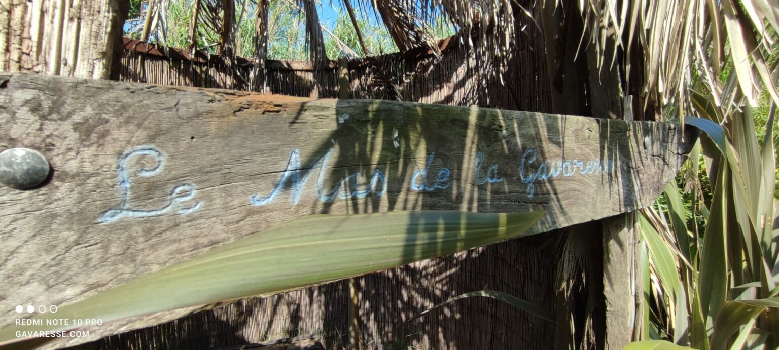 Panneau gravé 'Le Mas de la Gavaresse' sur une planche de tonneau, façade de la cabane écologique pour enfants dans le jardin.