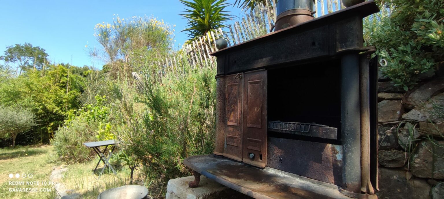 Barbecue rustique et éco-responsable de la Maison Gavaresse, avec le jardin méditerranéen en arrière-plan, au Pradet.