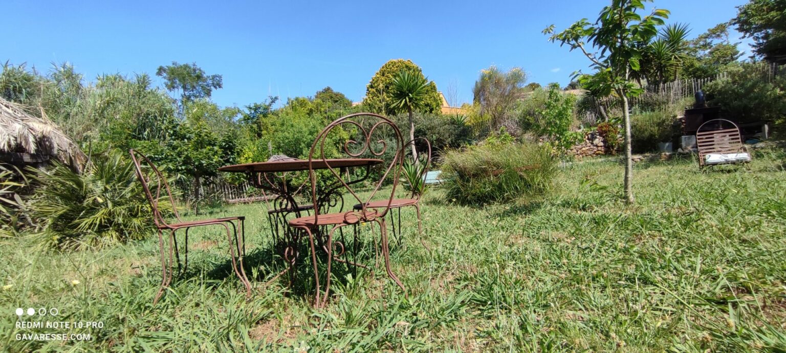 Table à manger ronde romantique en fer forgé avec chaises et fauteuils pour 4 personnes, située dans le jardin méditerranéen de la Maison Gavaresse au Pradet.