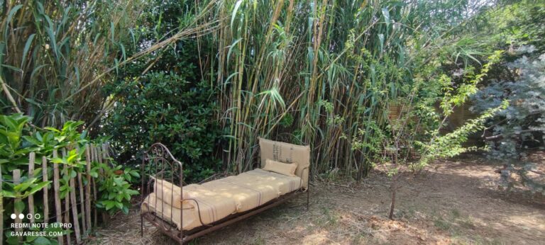 Ancien lit d'enfant en fer forgé transformé en banquette de jardin avec coussins en toile de jute recyclée au Mas de la Gavaresse au Pradet.