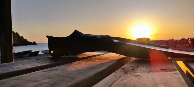 Palme de plongée posée sur une table en bois face au coucher de soleil sur la plage des Bonnettes au Pradet après une session de snorkeling.