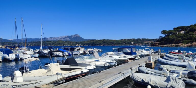 Bateaux de location et de tourisme amarrés aux quais du petit port des Oursinières au Pradet sous un ciel bleu.