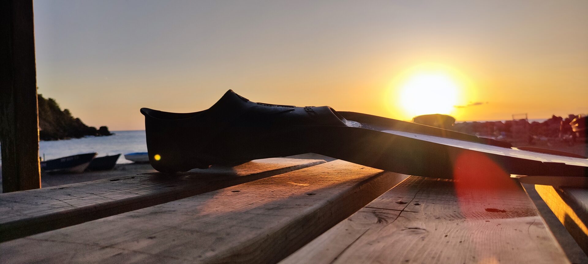 Eine Apnoe-Flosse liegt auf einem Holztisch während eines goldenen Sonnenuntergangs am Strand Plage des Bonnettes in Le Pradet nach dem Tauchen.