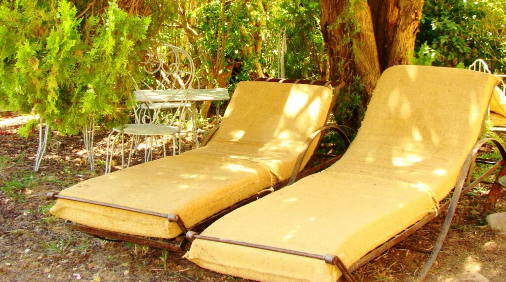 Transats à l'ombre des arbres dans le jardin écoresponsable du Mas de la Gavaresse.