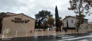Bâtiment du Pôle Culturel de la ville du Pradet sous un ciel gris et la pluie, abritant la bibliothèque et la ludothèque.